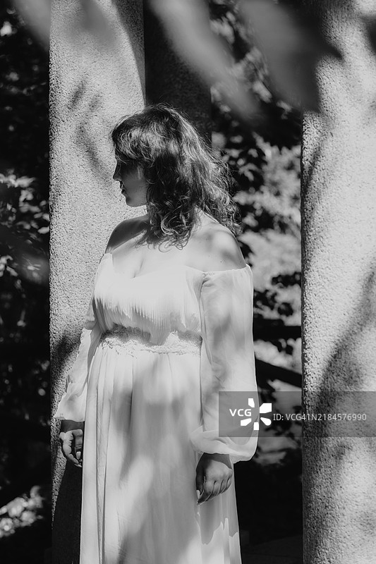 年轻女性肖像，站在石柱旁，黑白色调图片素材