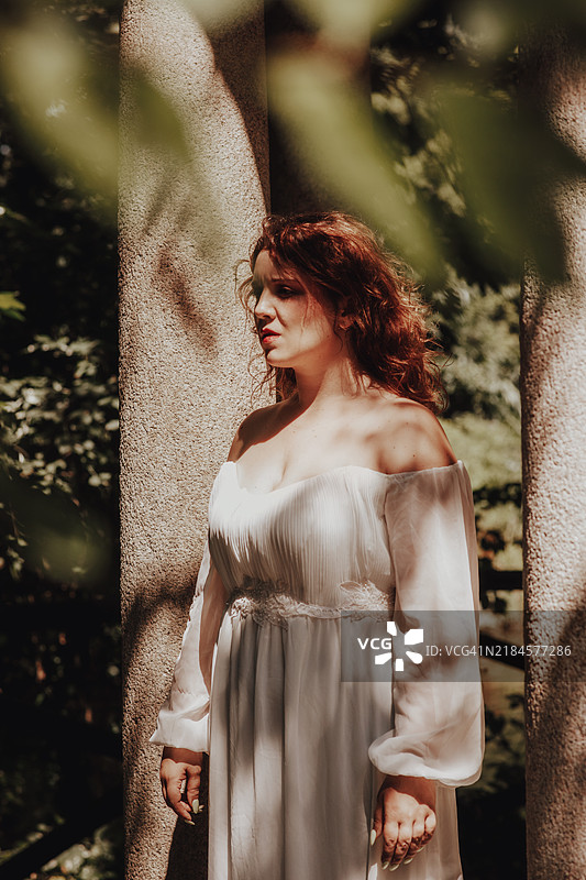 年轻的红发女性肖像，站在石柱旁，脸上带着痛苦的表情图片素材