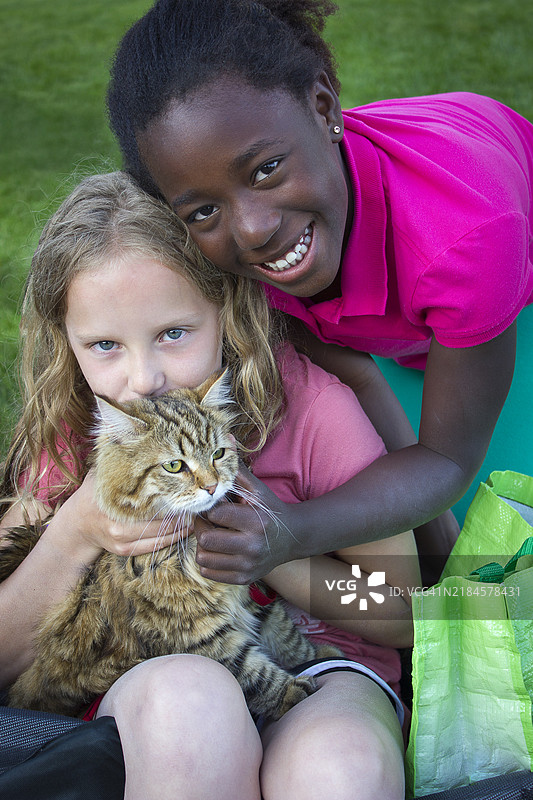 两个孩子在户外照顾和玩耍猫咪图片素材