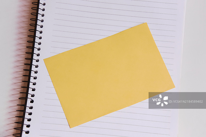 一张黄色便签纸或自粘便条纸，背景为笔记本图片素材