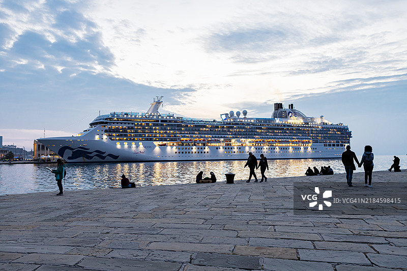 人们在莫洛·奥达切（Molo Audace）旁，背景是游轮。图片素材