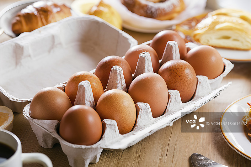 从上方俯视一个装满新鲜棕色母鸡蛋的纸箱，准备用于烘焙、烹饪或早餐，呈对角视角。图片素材