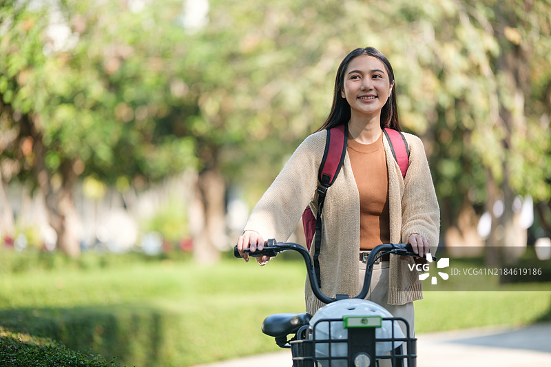 公园里微笑的女性与自行车和音乐耳机的肖像图片素材