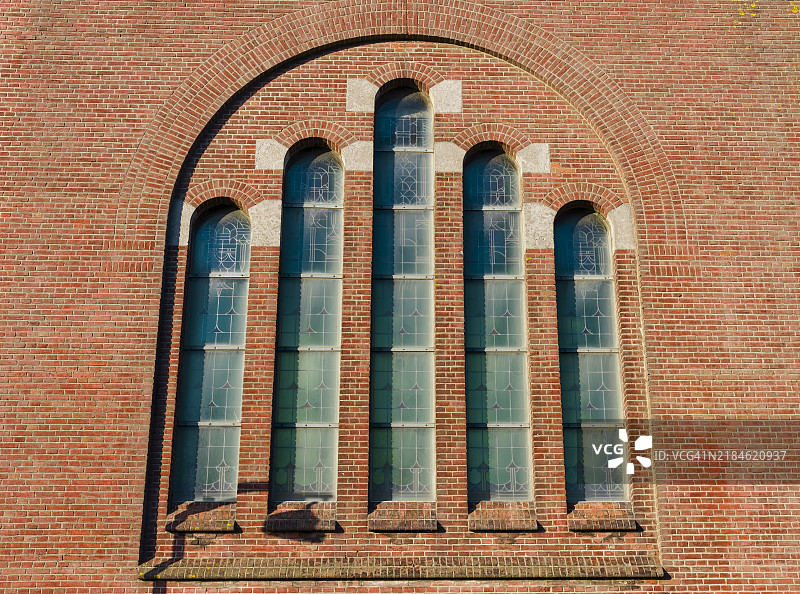 旧天主教教堂石墙上垂直放置的彩色玻璃窗图片素材