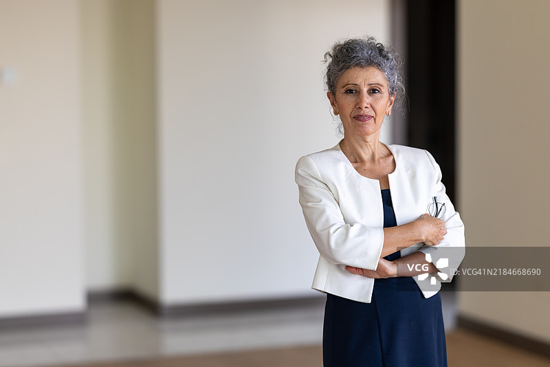 微笑的老年女性销售员在家中双臂交叉的肖像图片素材