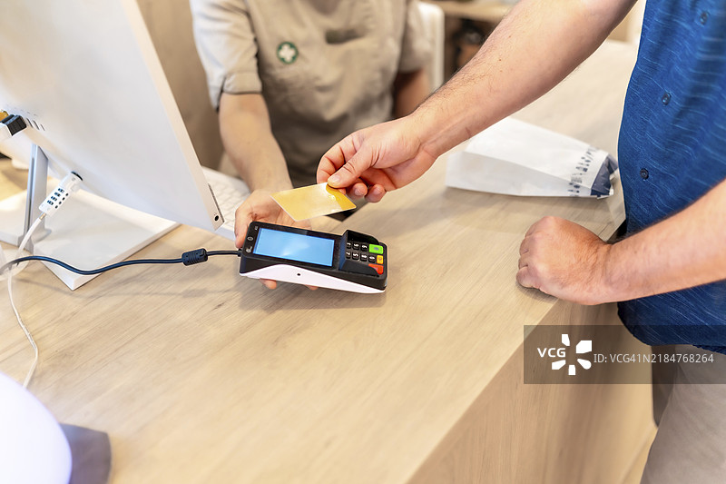 一名男子在药店使用信用卡购买药品的手部特写照片图片素材