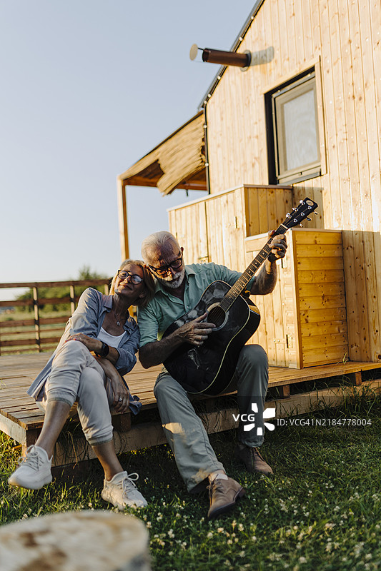老年夫妇在他们的豪华露营小屋的露台上弹奏木吉他，享受美好时光图片素材