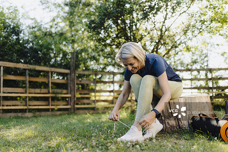 一位年长女性在户外锻炼时系鞋带图片素材