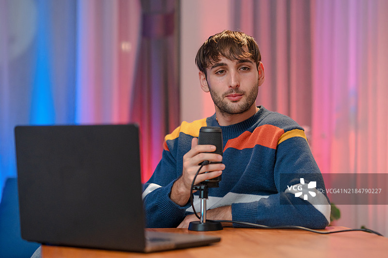 实时互动：一位男博主手持麦克风，在舒适的空间里与热情的粉丝分享生活和建议。图片素材