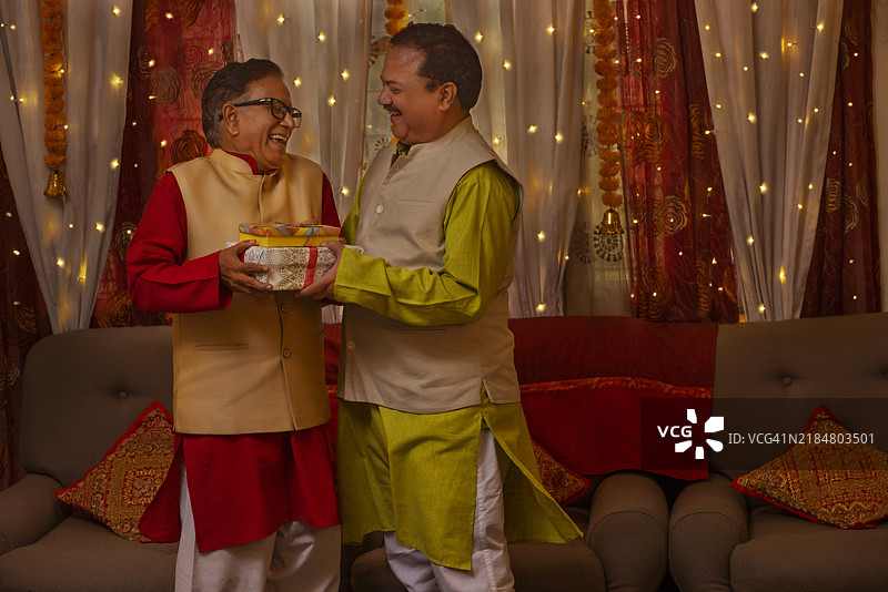 父亲和儿子穿着传统服装在排灯节交换礼物图片素材