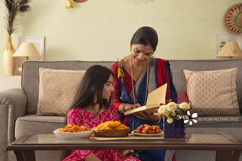 母亲和女儿在客厅里一起阅读一本书图片素材