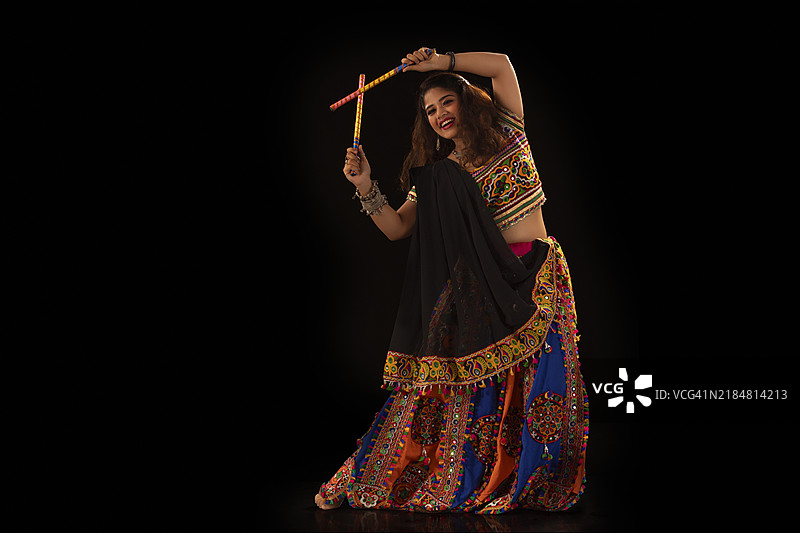 年轻女性在纳瓦拉特里庆祝活动中快乐地表演丹迪亚拉斯舞蹈的肖像图片素材