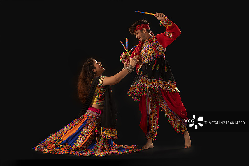 年轻快乐的情侣在纳瓦拉特里庆祝活动中表演丹迪亚拉斯舞。图片素材