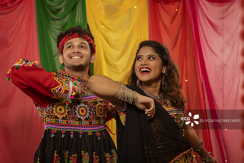 年轻的古吉拉特夫妇在纳瓦拉特里庆祝活动中表演丹迪亚拉斯舞蹈的肖像图片素材