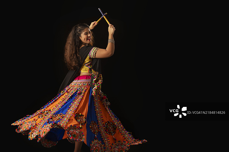 年轻女性在纳瓦拉特里庆祝活动中快乐地表演丹迪亚拉斯舞蹈的肖像图片素材