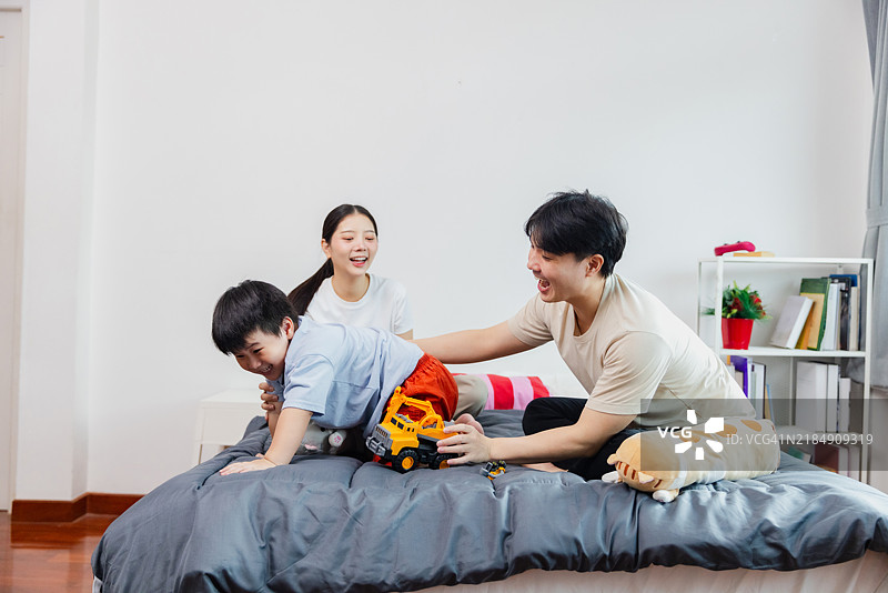 一家人在阳光明媚的下午，在温馨明亮的卧室里玩耍，玩着一辆玩具卡车。图片素材