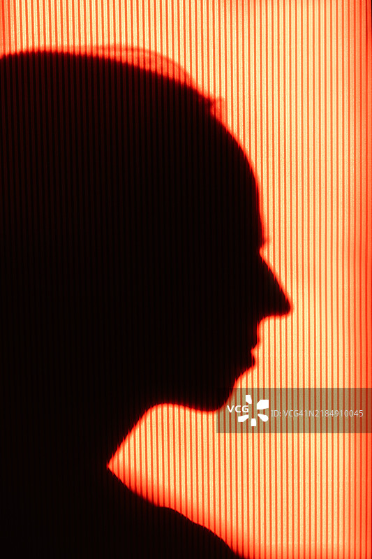 阳光明媚的日子里，橙色明亮背景上的女性剪影。图片素材