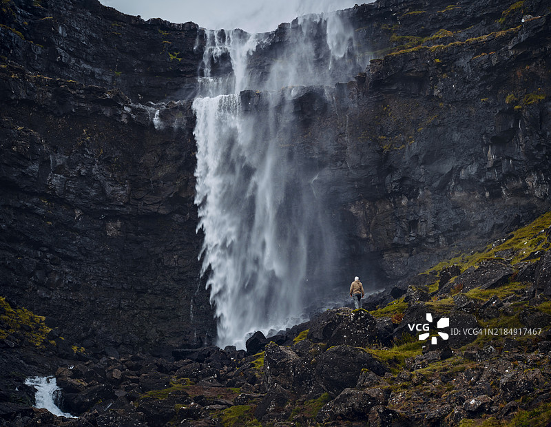 无忧无虑的游客背影欣赏法罗群岛的福萨瀑布。图片素材