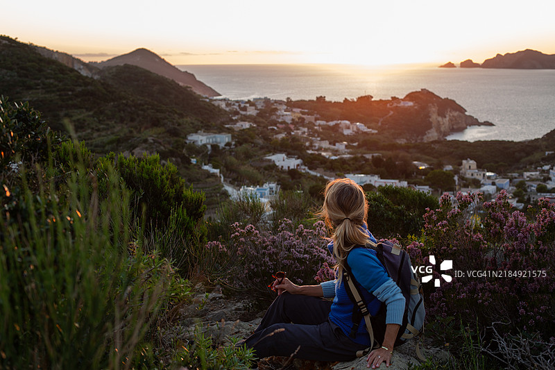 女人在日落时分徒步旅行，享受山顶的海景图片素材