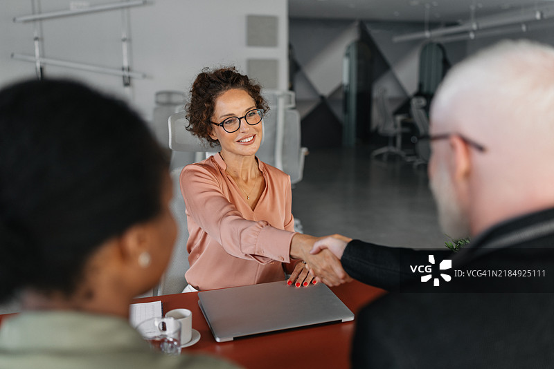 握手象征着在充满活力的办公室空间中的协议。图片素材
