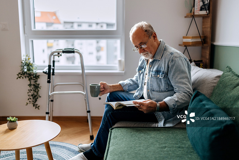 老年男子在沙发上放松地阅读书籍图片素材