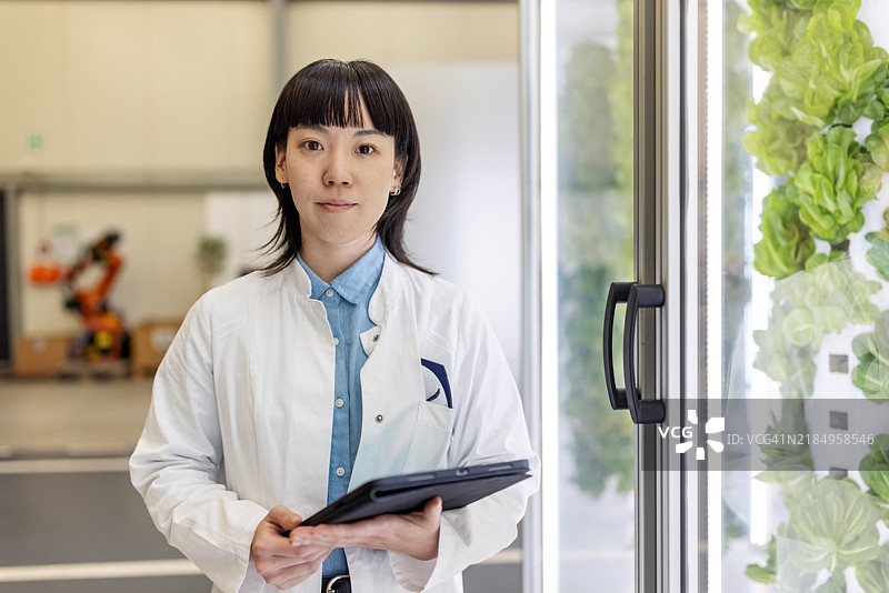 亚洲女性农学家在垂直农业设施中使用数字平板电脑工作图片素材