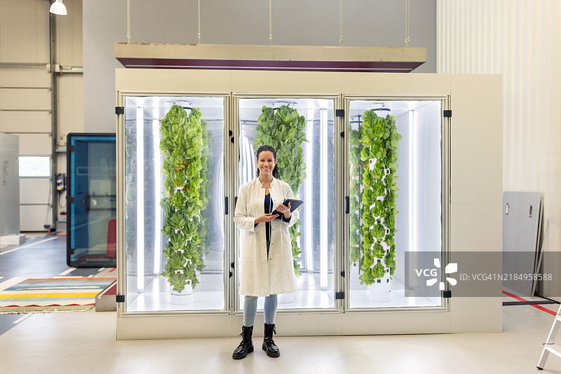 微笑的女性农学家在垂直农业设施中使用数字平板电脑图片素材