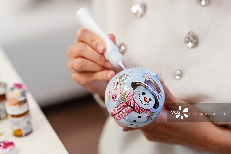 女性艺术家在家中绘制手工圣诞球图片素材