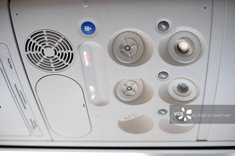 飞机客舱内的顶部面板，显示空气通风口、阅读灯和呼叫按钮。干净的设计和功能性得到了突出，适合与航空旅行、航空和机上设施相关的主题。图片素材