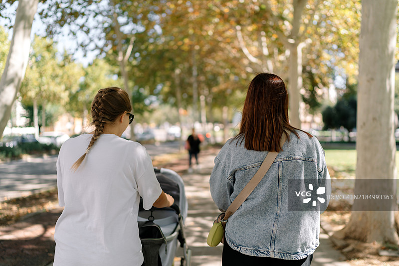 两个年轻女性在公园里推着婴儿车聊天图片素材
