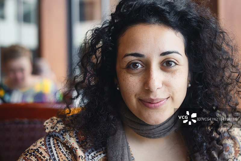 一位美丽的白人女性，长着黑色卷发，正视镜头，穿着连衣裙和围巾，来自美国。图片素材