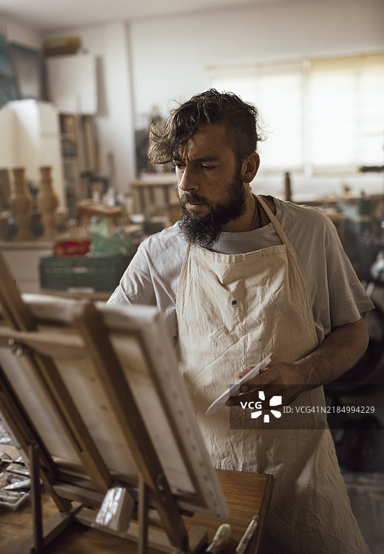 年轻的企业家画家在他的艺术工作室里创作一幅画的垂直视角图片素材