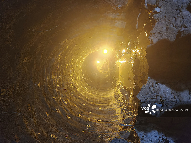 隧道被温暖的灯光照亮，营造出发光的氛围，水洼反射出光线。图片素材