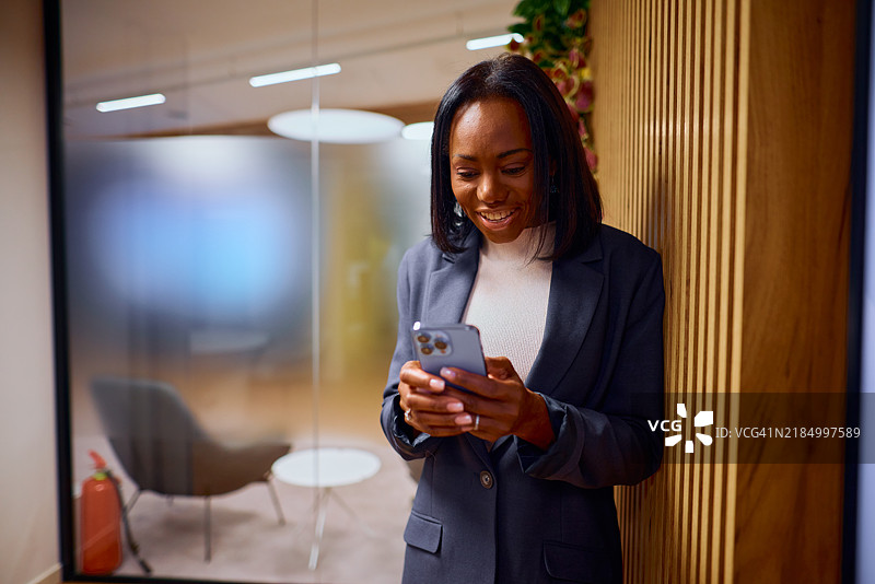 自信的黑人女商人在现代办公室使用智能手机图片素材