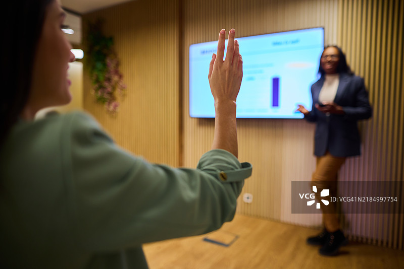 女性在办公室的企业演示中与演讲者互动图片素材