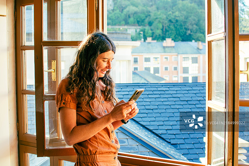 女人在窗边看手机图片素材