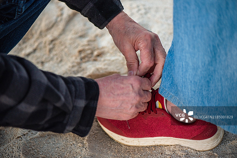 老年男子在湖边帮助妻子系鞋带图片素材