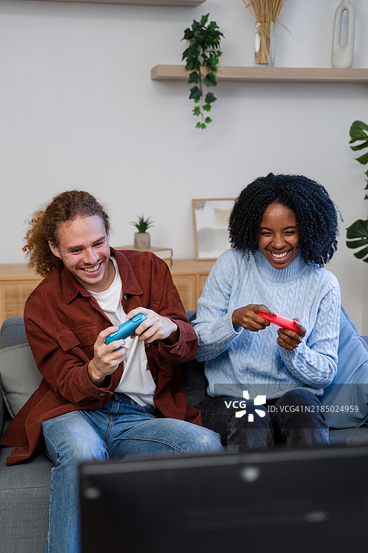 快乐的情侣在沙发上玩电子游戏图片素材