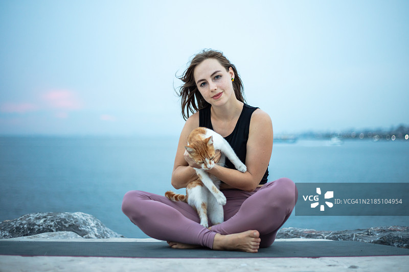 年轻女性抱着一只姜黄色的流浪猫。图片素材