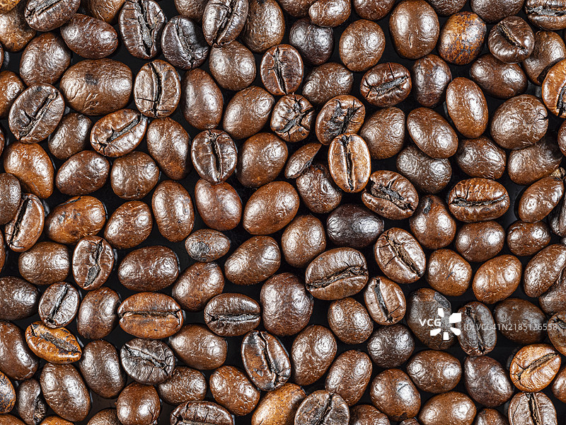 烤制的罗布斯塔咖啡豆特写，放置在平坦的表面上。图片素材