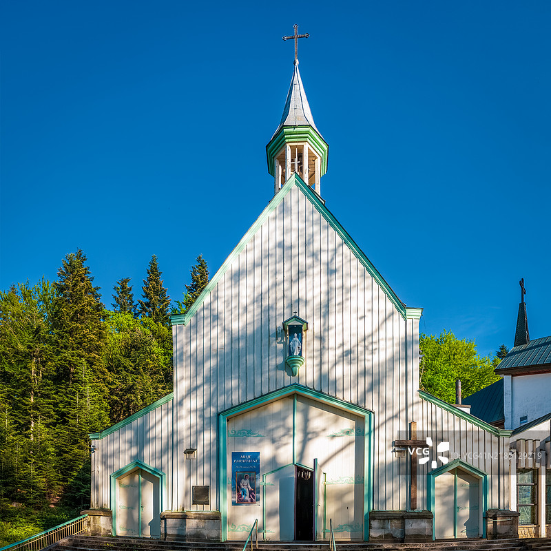 宁静的木制教堂坐落在阳光明媚的森林中图片素材