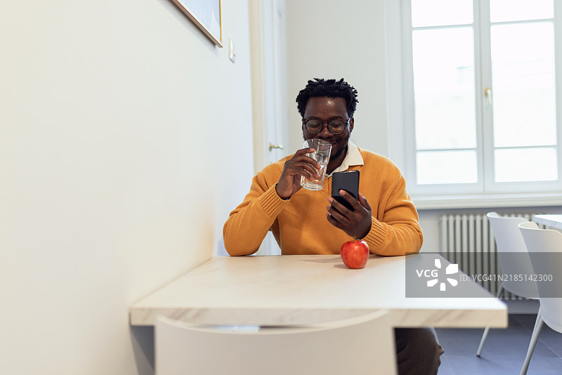 一位微笑的非裔美国男性在工作间隙使用手机图片素材