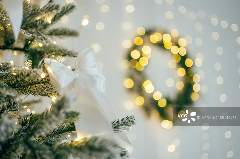 装饰华丽的圣诞树，闪烁的灯带聚焦，墙上挂着花环，光斑背景图片素材