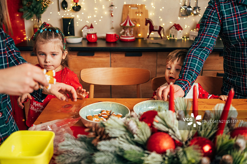 带着人工耳蜗的女孩在家与家人一起享用姜饼，庆祝圣诞节。图片素材