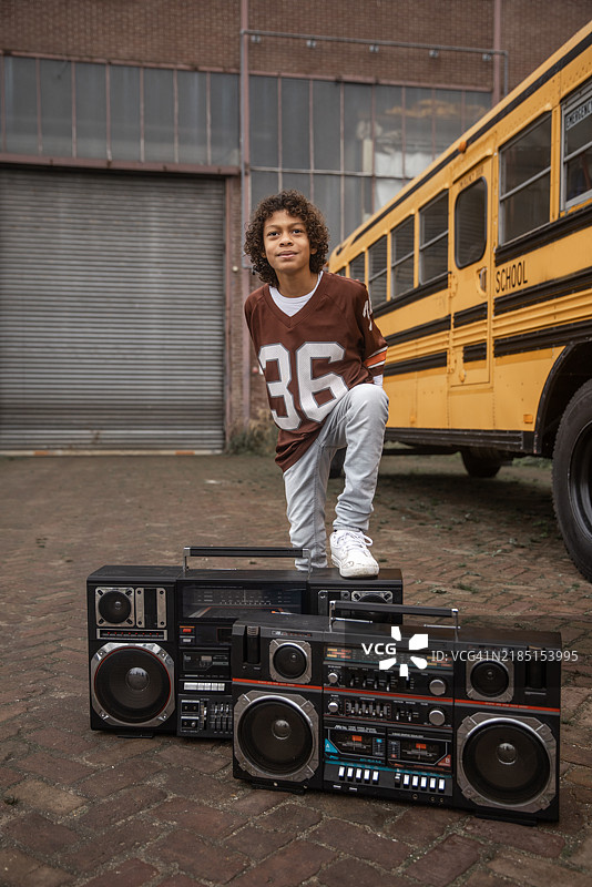 一位混血男孩的肖像，代表1980年代的嘻哈文化，背景是一辆校车。图片素材