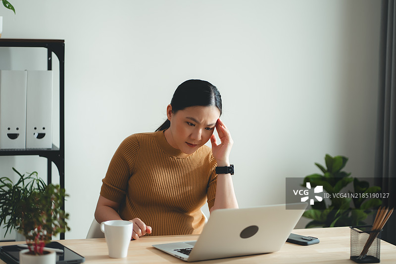 亚洲孕妇在家办公时因头痛而感到不适。图片素材