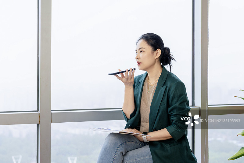 一位亚洲白领女性在办公室使用手机的肖像图片素材