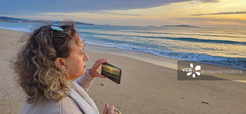 女士在日落时拍照。图片素材