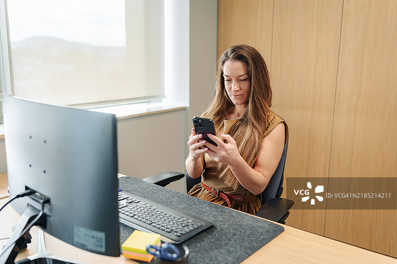 优雅的中年女商人在办公室使用智能手机图片素材
