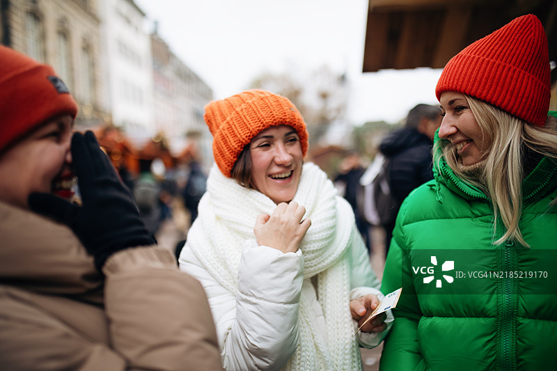 三位快乐的女性在圣诞市场上。图片素材
